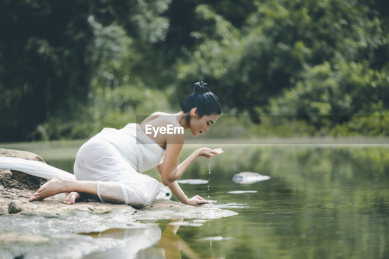 Full length of woman drinking water from river