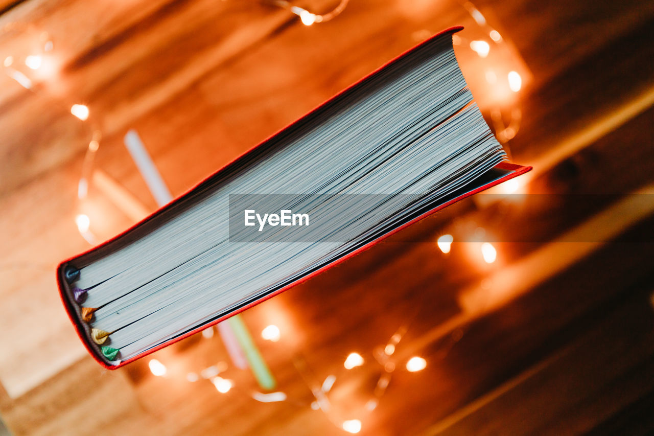 High angle view of book by illuminated lights on table