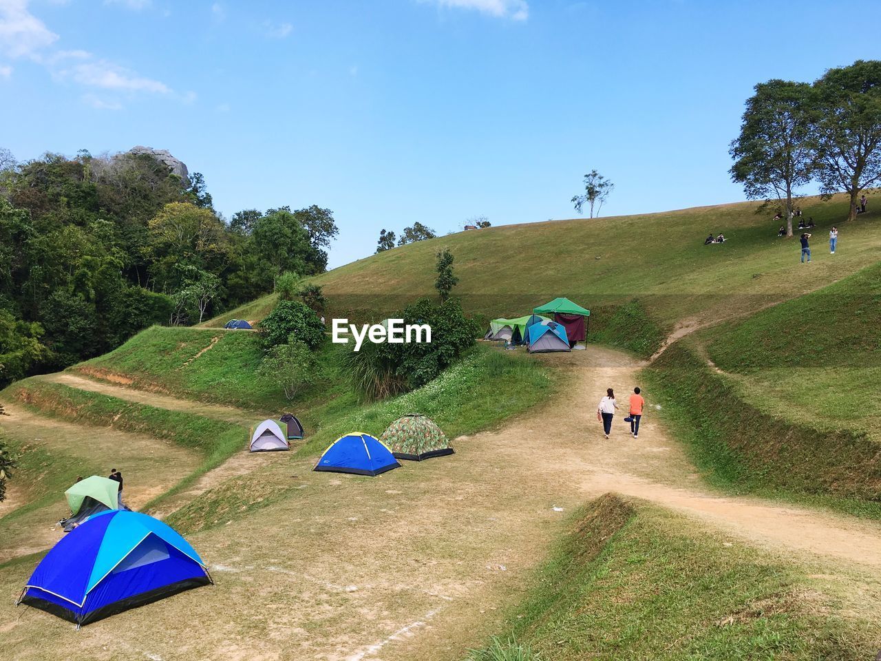 People walking on land against blue sky