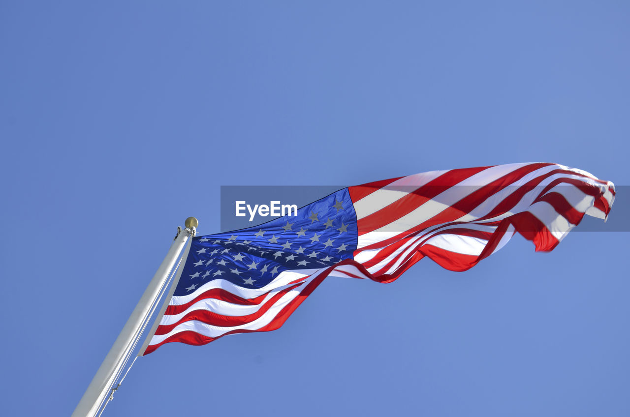 Low angle view of north american flag against clear blue sky