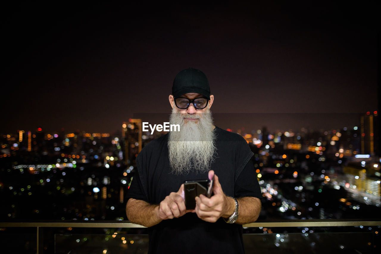 Full length of man using mobile phone at night