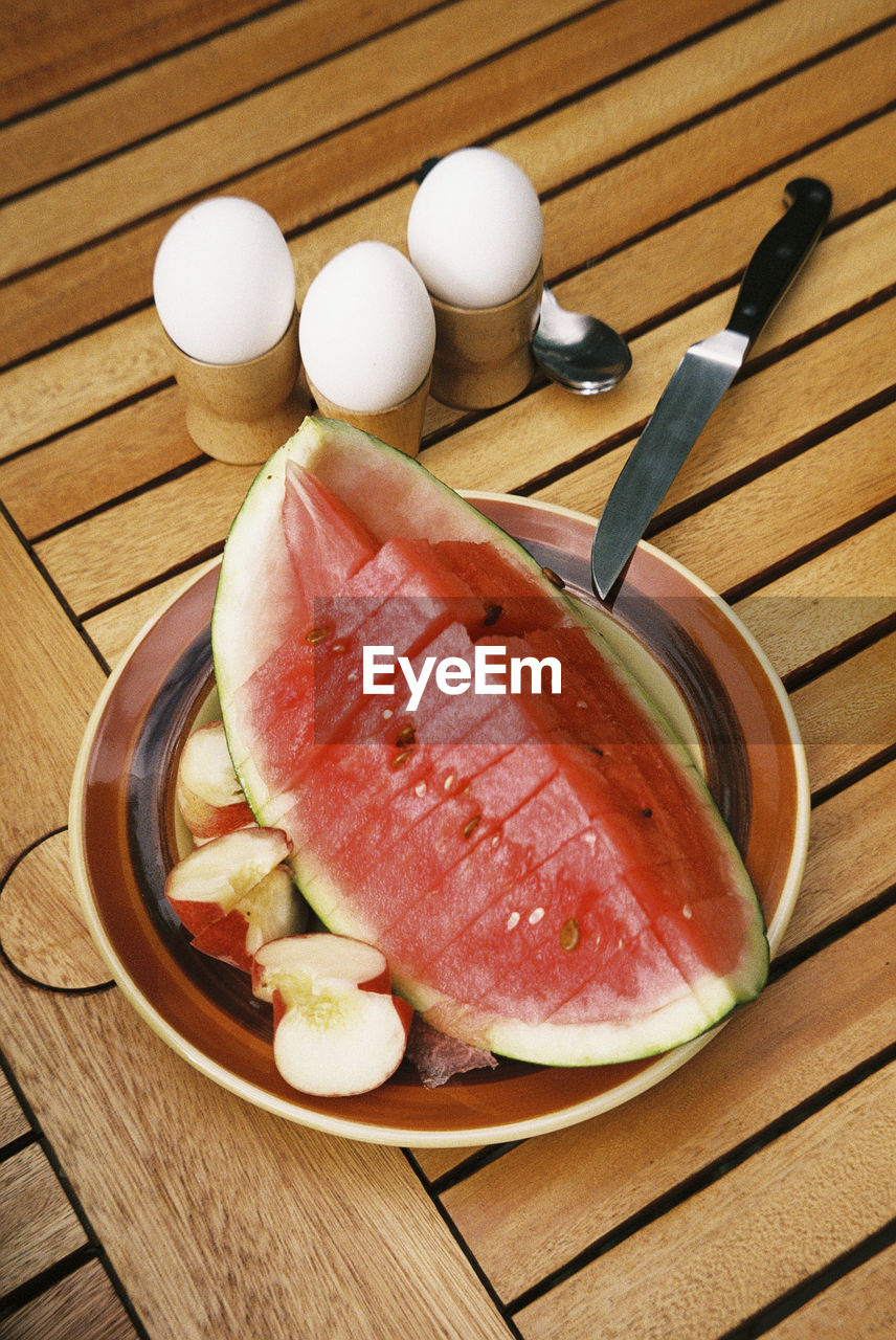 High angle view of breakfast with eggs an watermelon on table