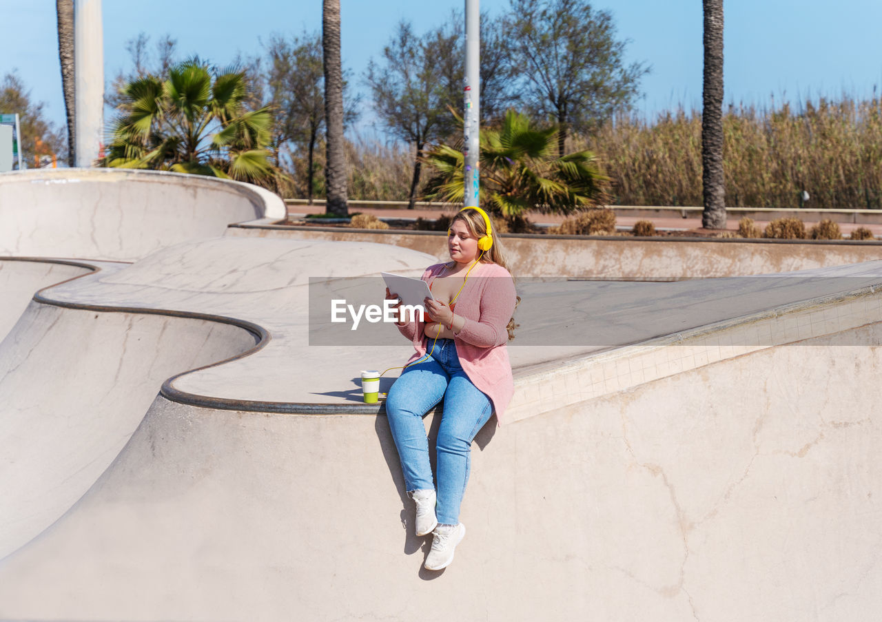 Full length of young woman sitting in skateboard park