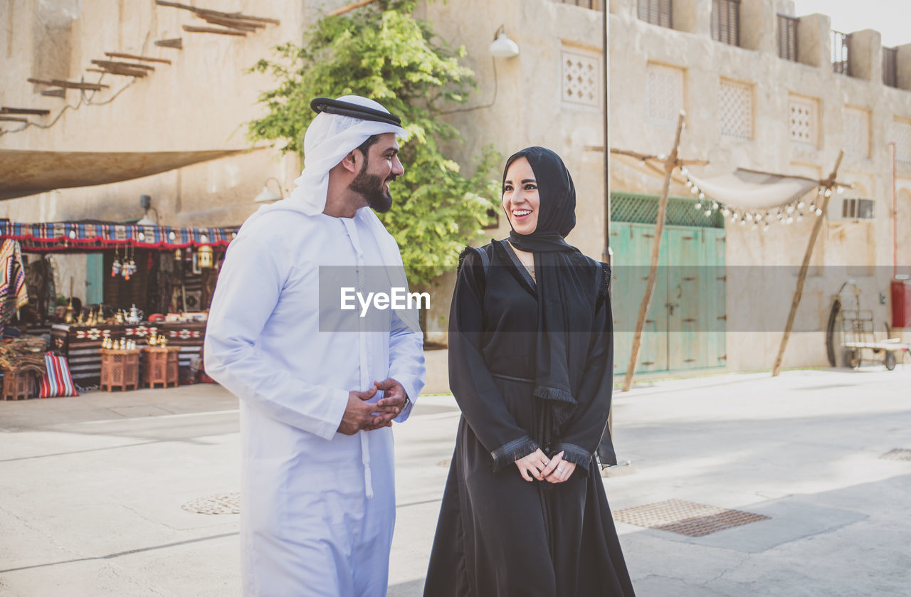 Smiling couple talking while walking on street in town