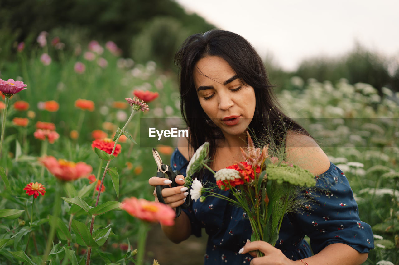 A young woman prune flowers in a floristic flower farm. woman florist.