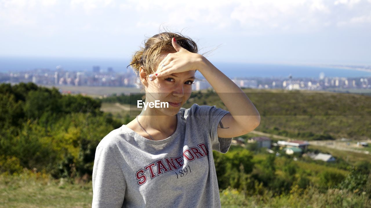 Portrait of young woman standing against sky