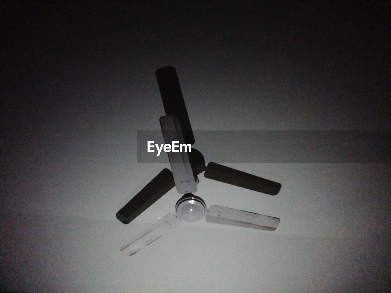 Low angle view of ceiling fan hanging from ceiling in darkroom