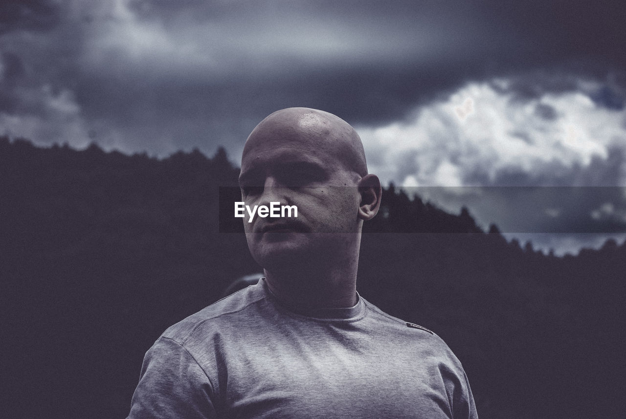 Close-up of mature man against mountain and cloudy sky