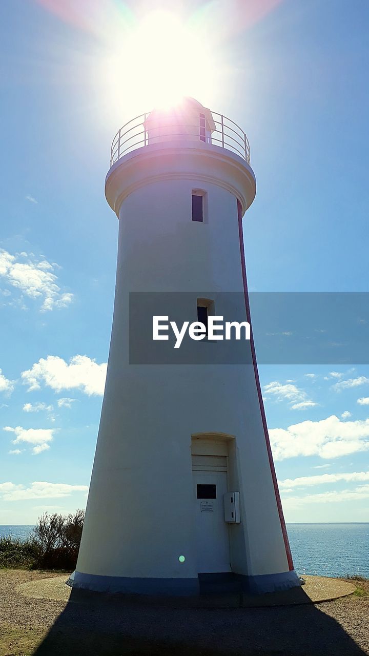 LIGHTHOUSE AMIDST BUILDINGS AGAINST SKY