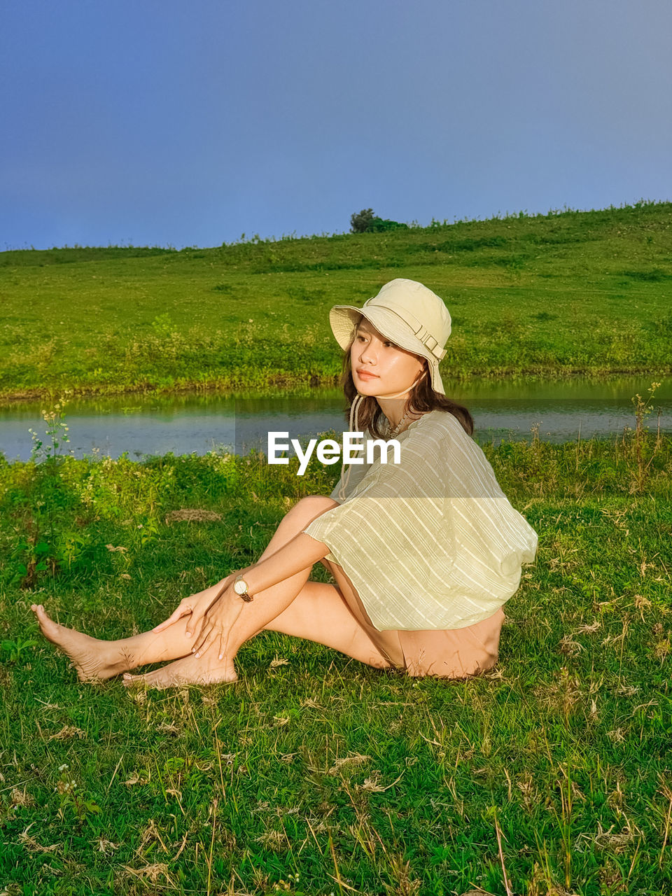 Portrait of young woman sitting on field against wonderful blue sky