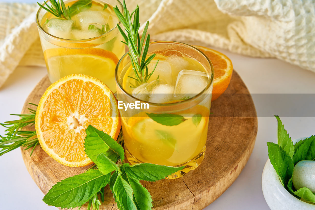 Summer refreshment drink. glass of water with orange, mint and rosemary. homemade lemonade with ice