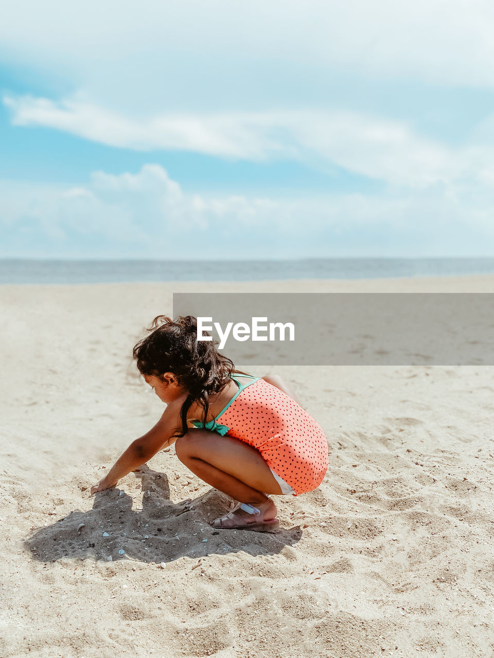 Diverse mixed race pre school age girl at sandy beach during summer having fun making memories