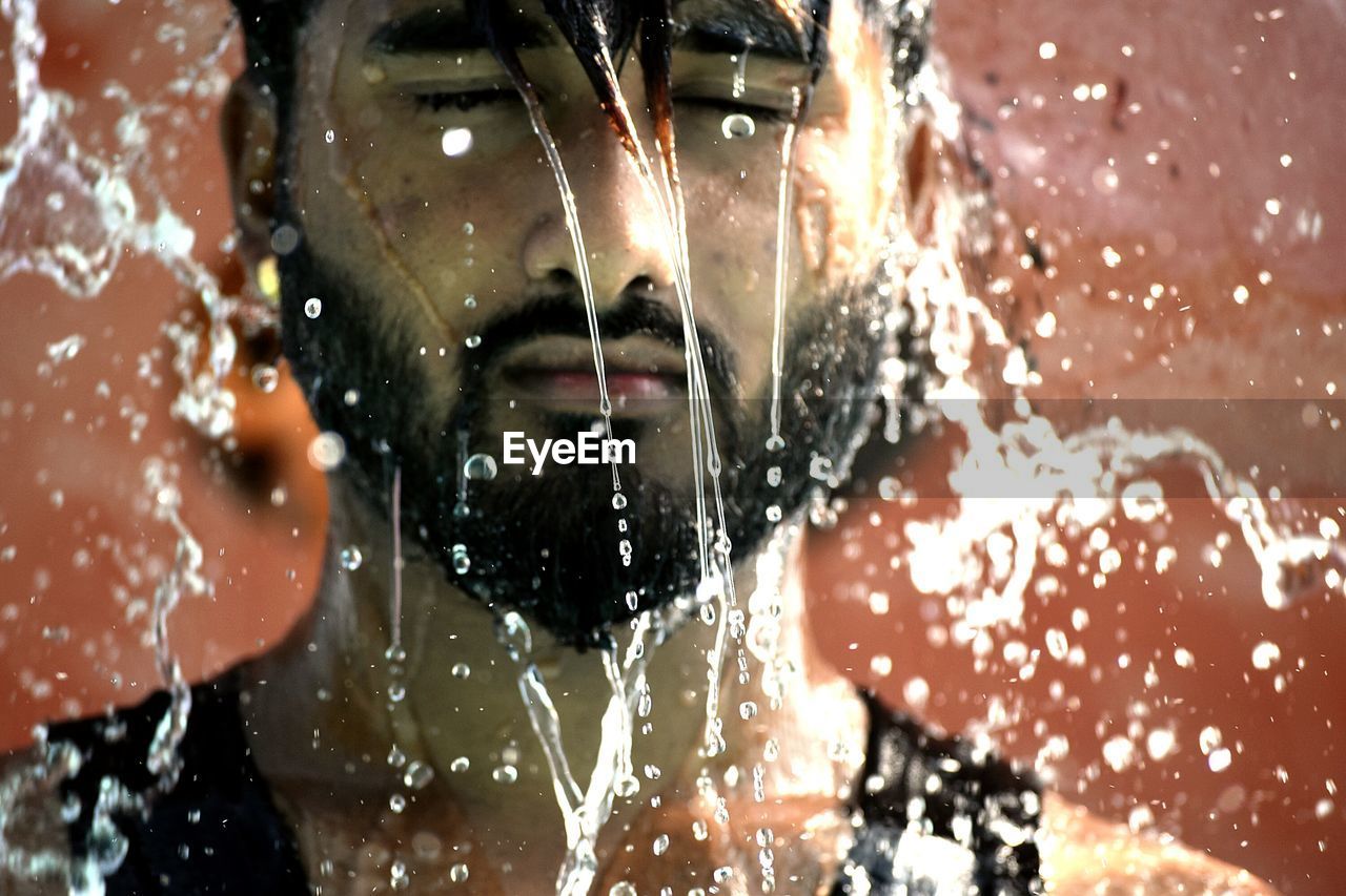 Water splashing on young man with beard