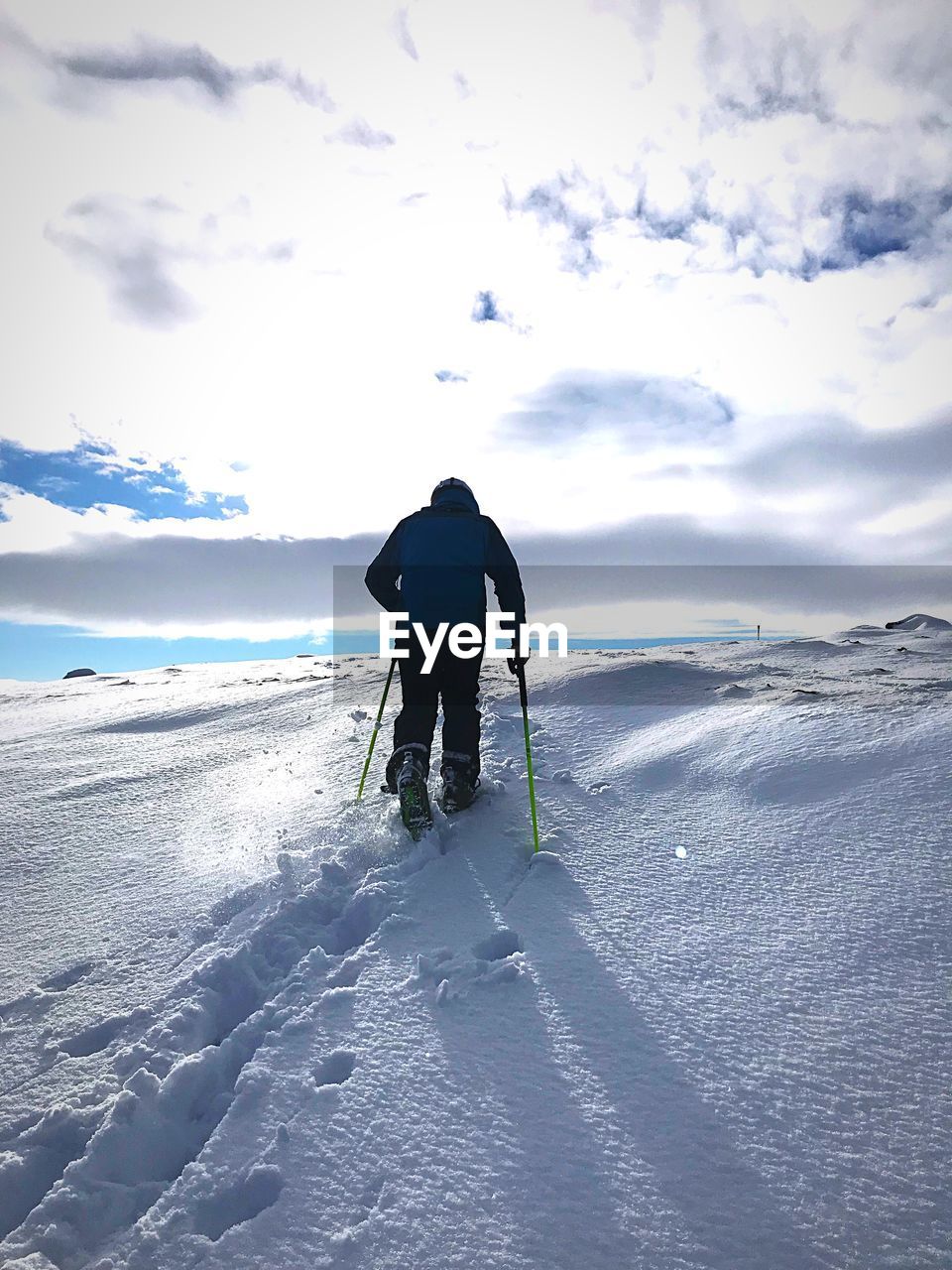 REAR VIEW OF PERSON ON SNOW AGAINST SKY