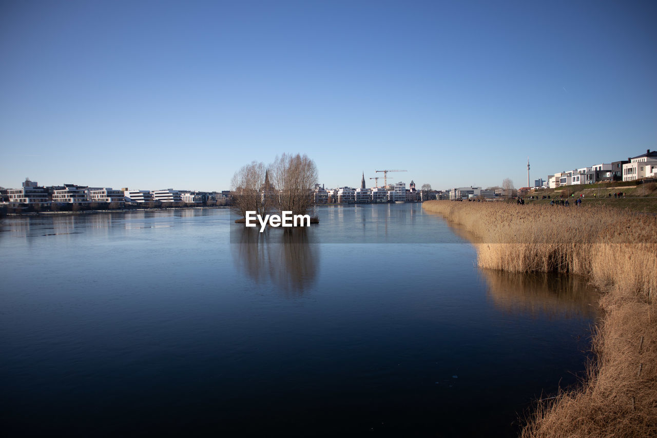 RIVER BY BUILDINGS AGAINST CLEAR SKY