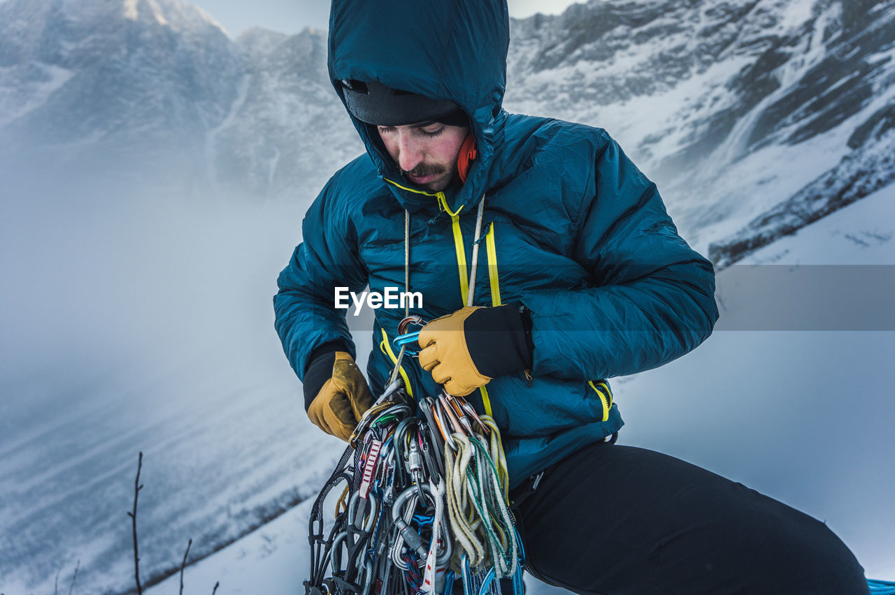 A man sorts through rock and ice climbing gear during a winter climb