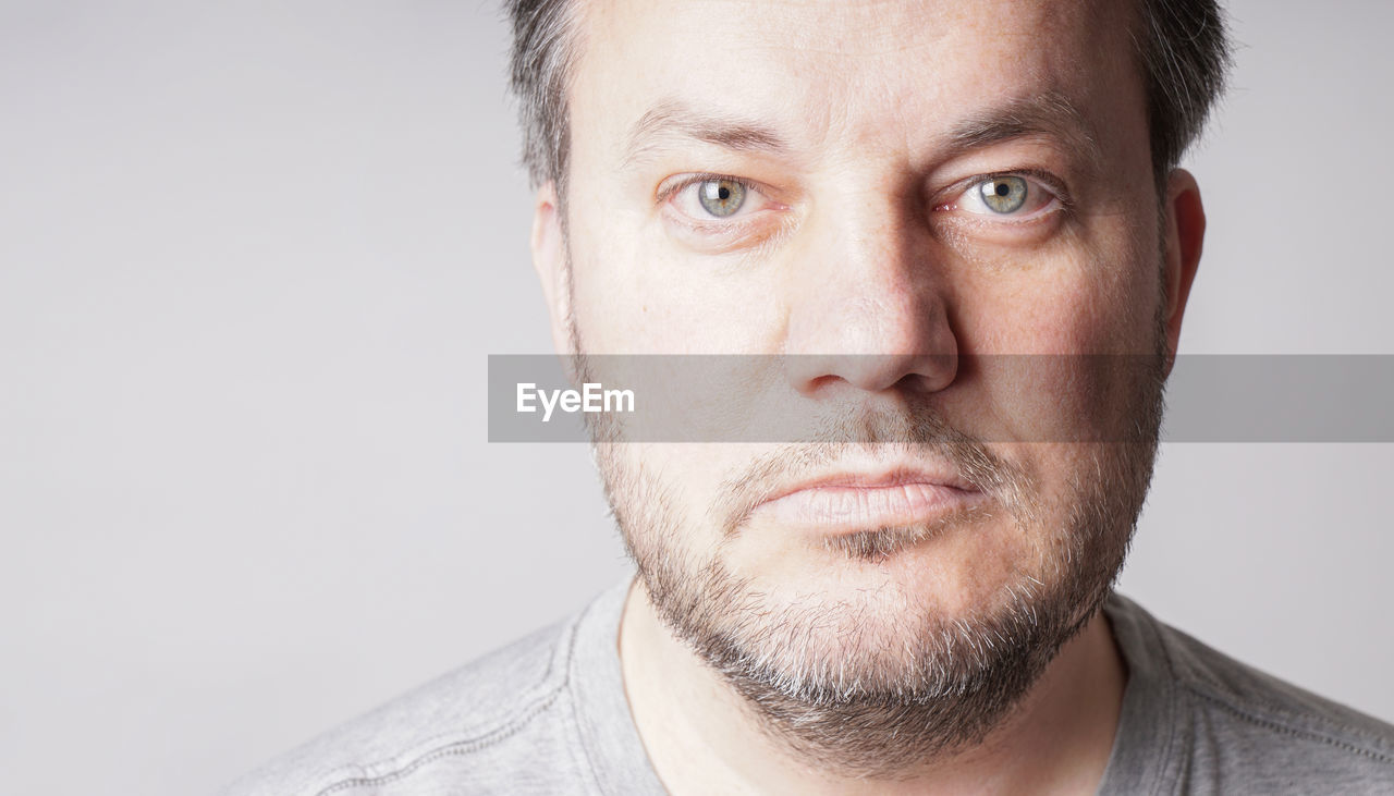 Mid adult man looking at camera - close crop headshot with copy space on gray background