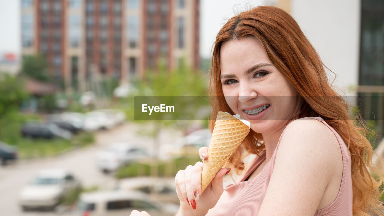 PORTRAIT OF A SMILING YOUNG WOMAN EATING ICE