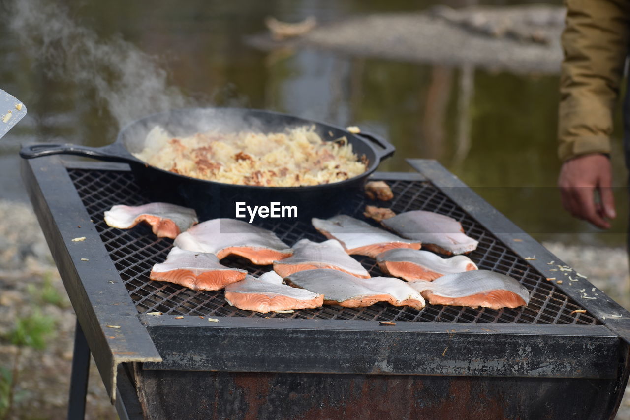 cropped hand of man preparing food on barbecue grill