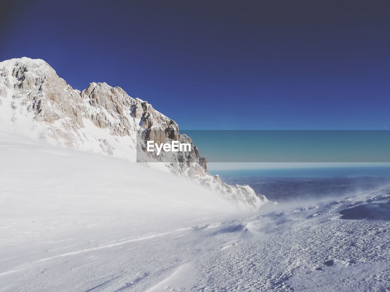 Scenic view of snow mountains against clear blue sky