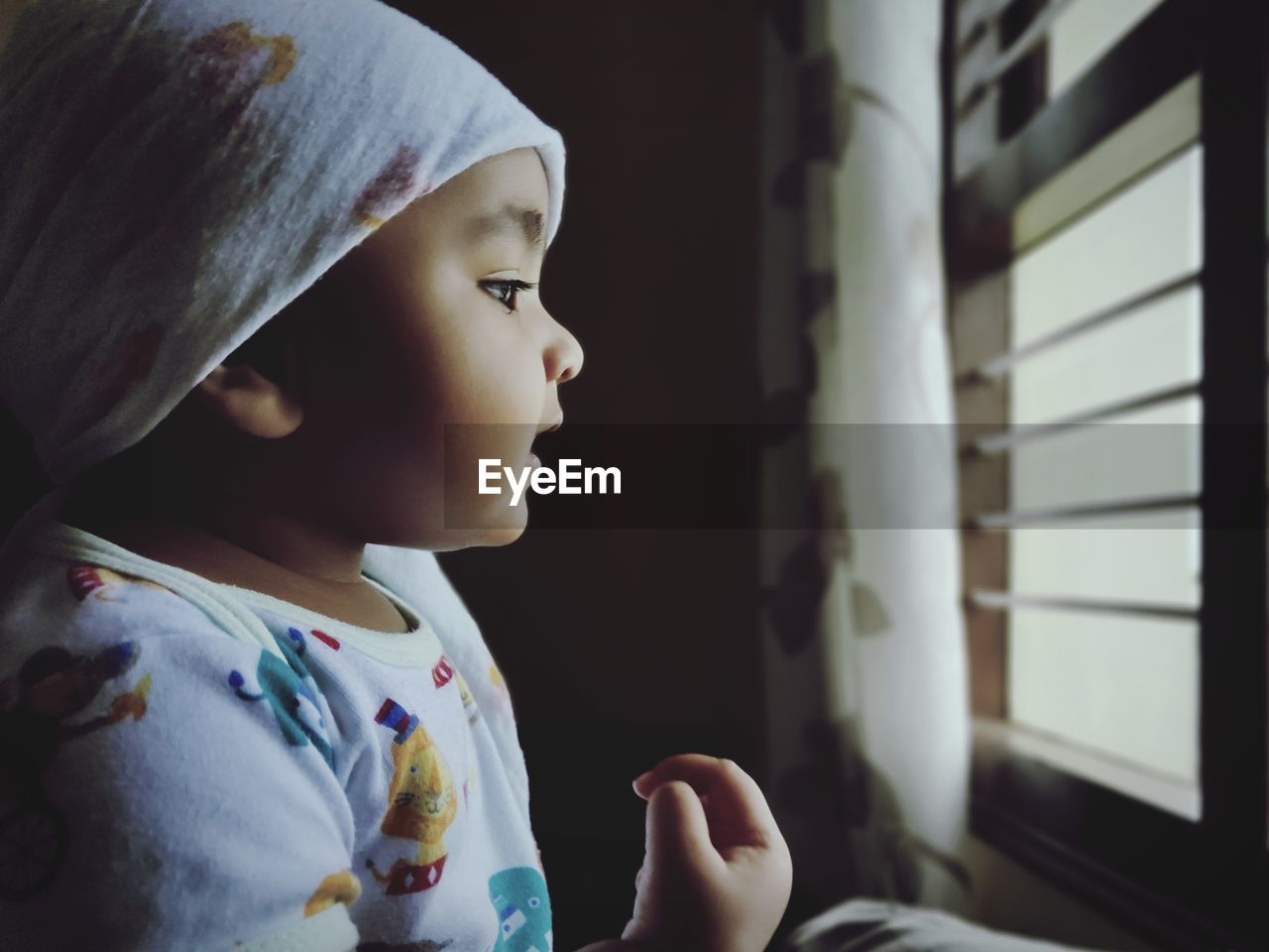 Close-up of cute baby girl looking through window