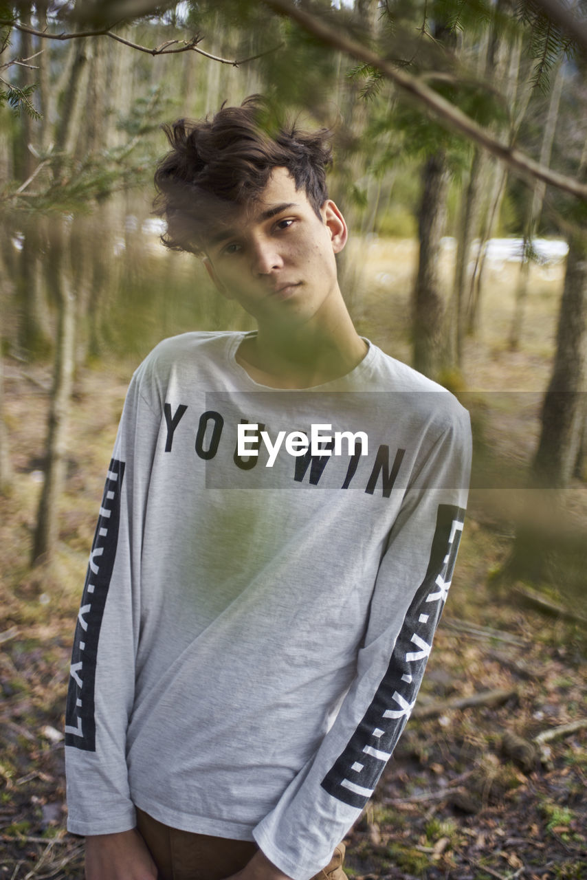 Portrait of young man standing at forest