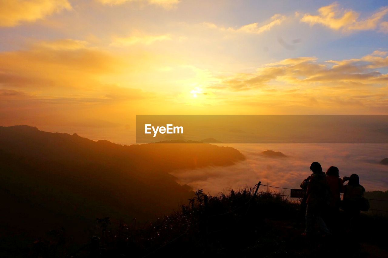 Silhouette people on mountain against sky during sunset