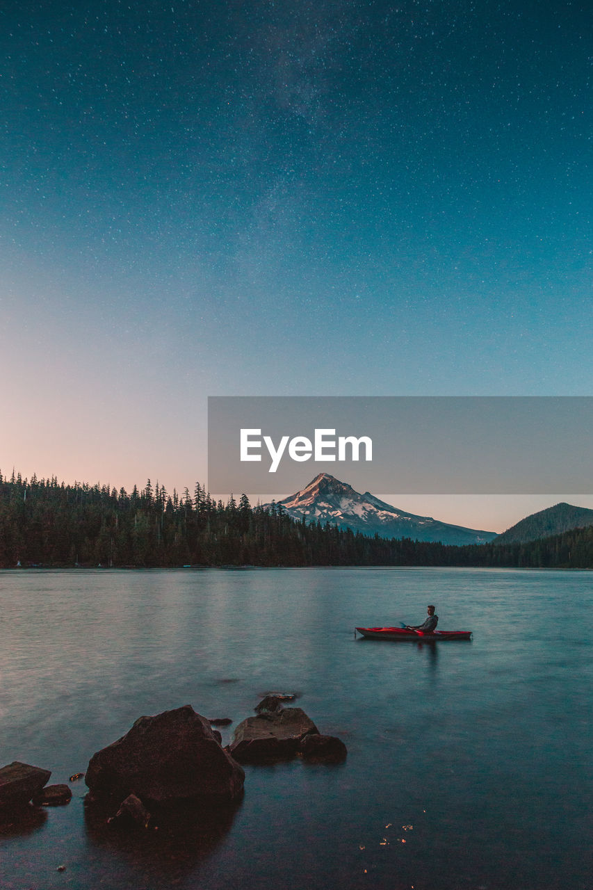 Man kayaking in lake against sky