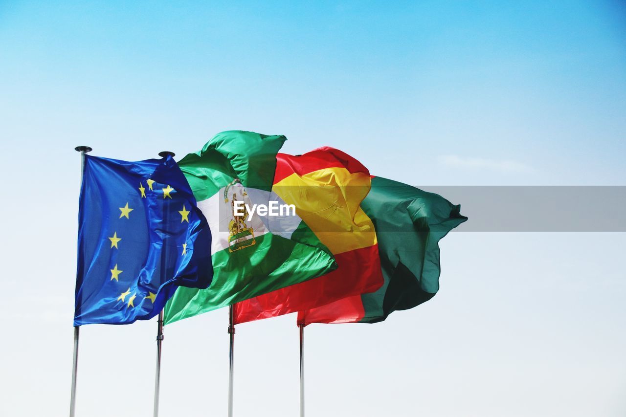 LOW ANGLE VIEW OF FLAGS AGAINST CLEAR BLUE SKY