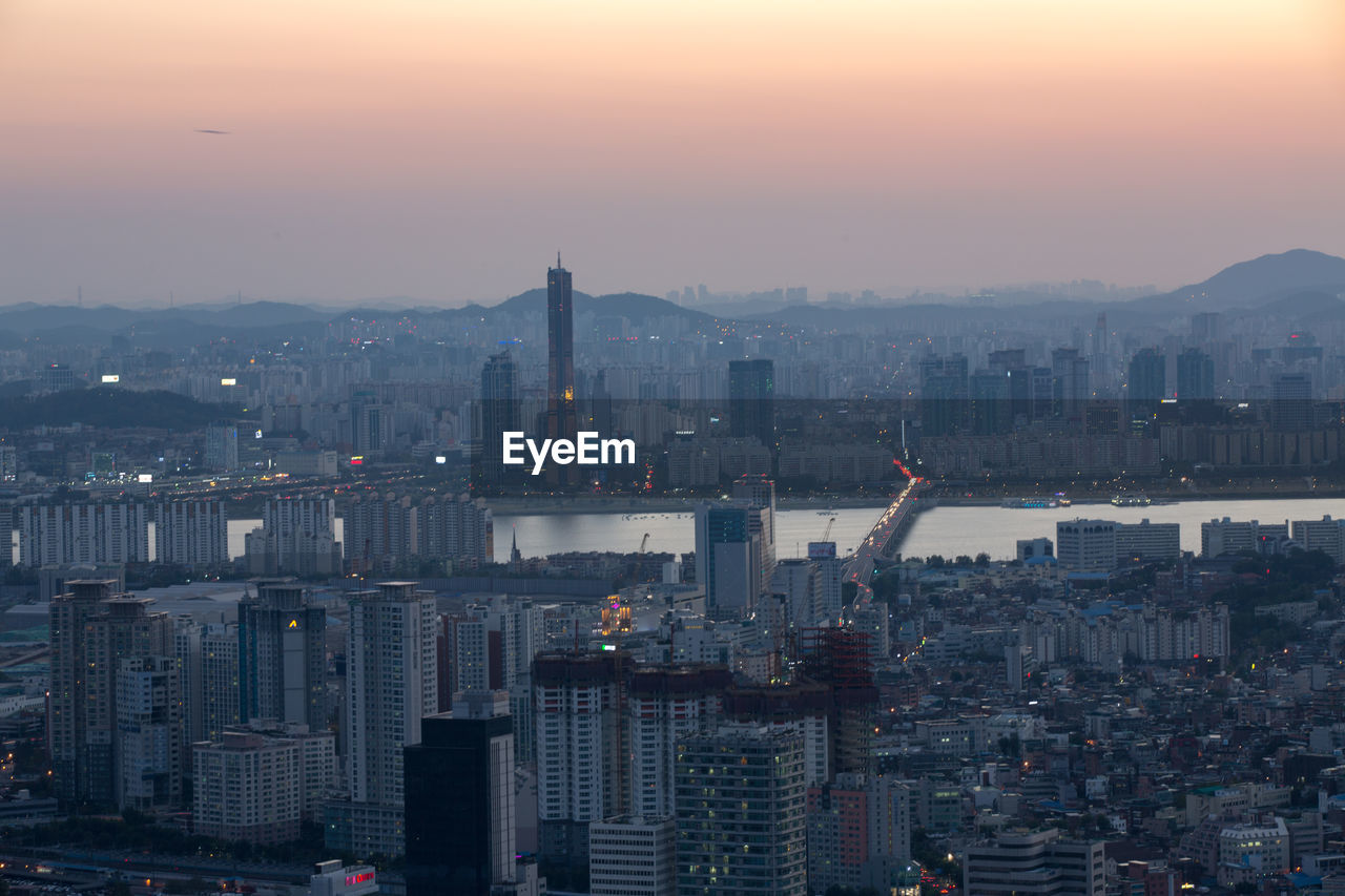 Illuminated cityscape against sky during sunset