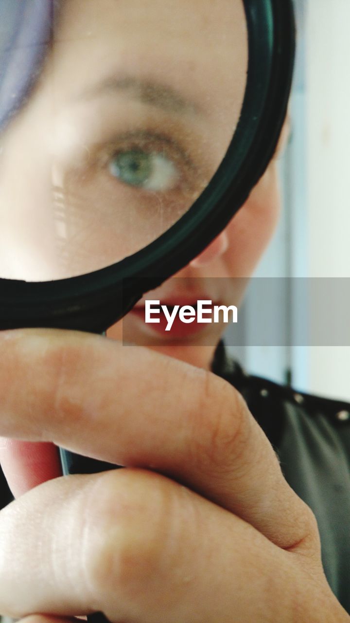 Woman holding magnifying glass in front of her eye