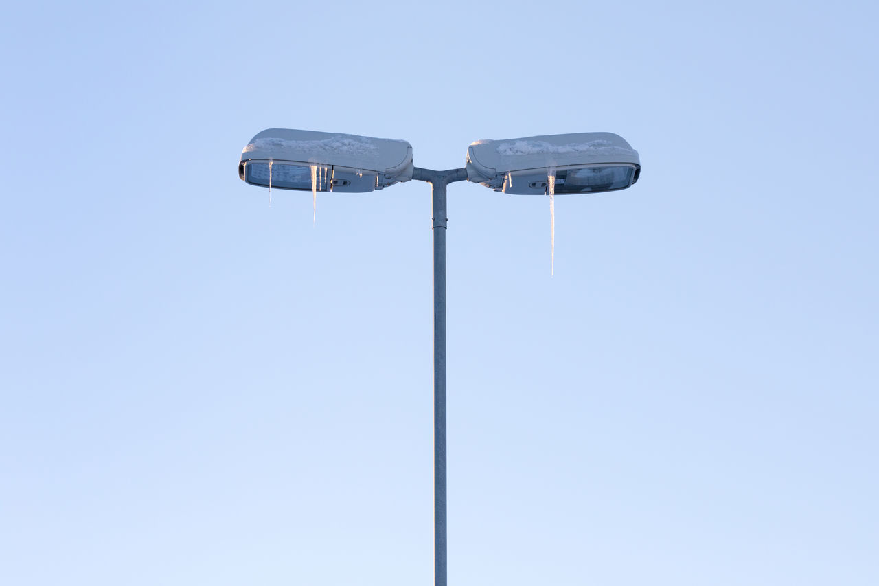 Low angle view of icicles on street light against clear sky