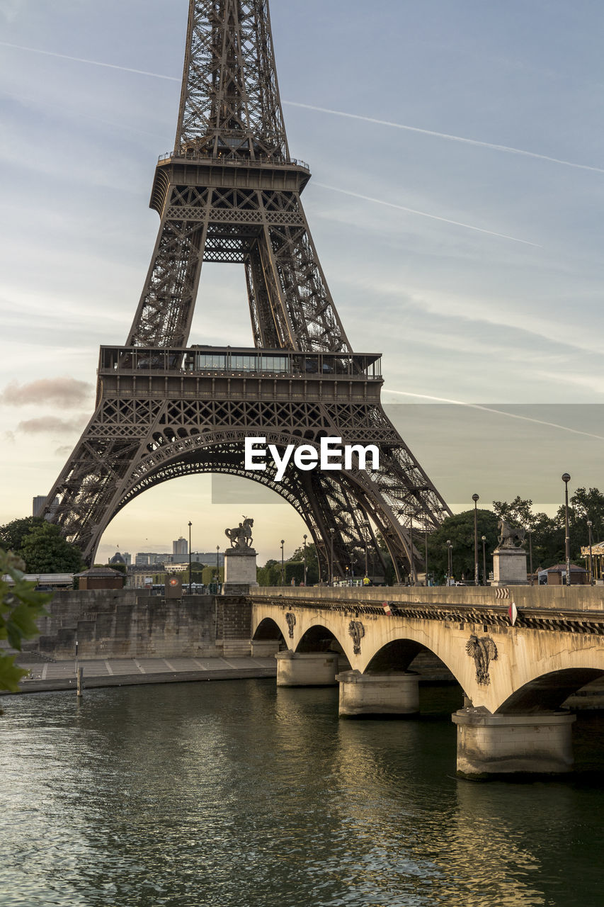 Eiffel tower by river seine in city against sky