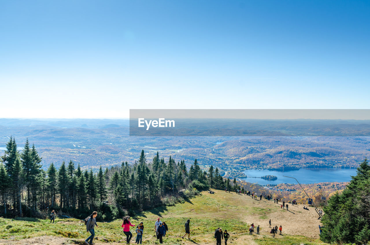 High angle view of people hiking on mountain against blue sky