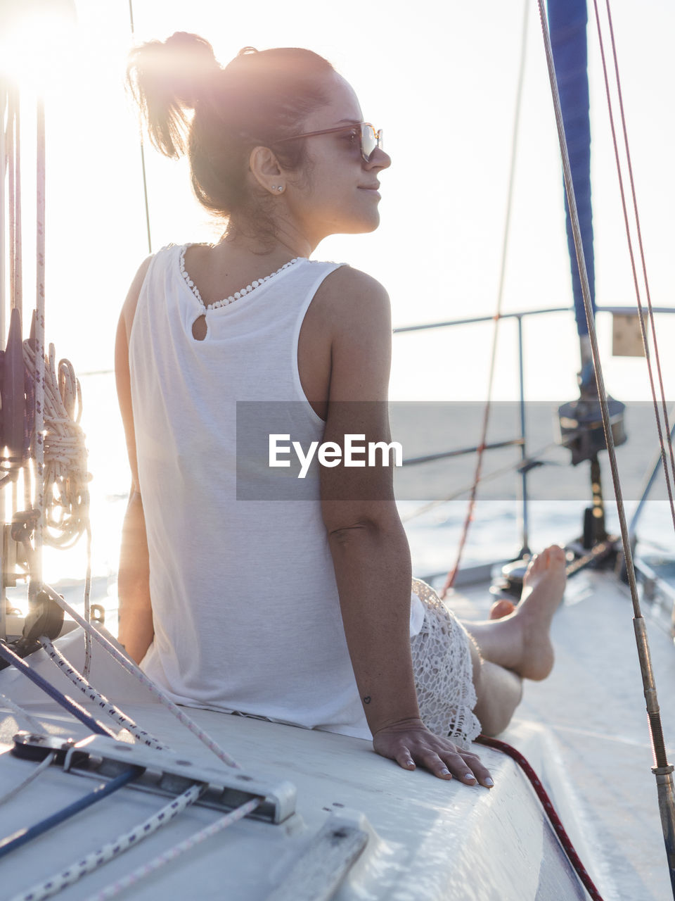 Rear view of woman looking away while sitting in sailboat against clear sky