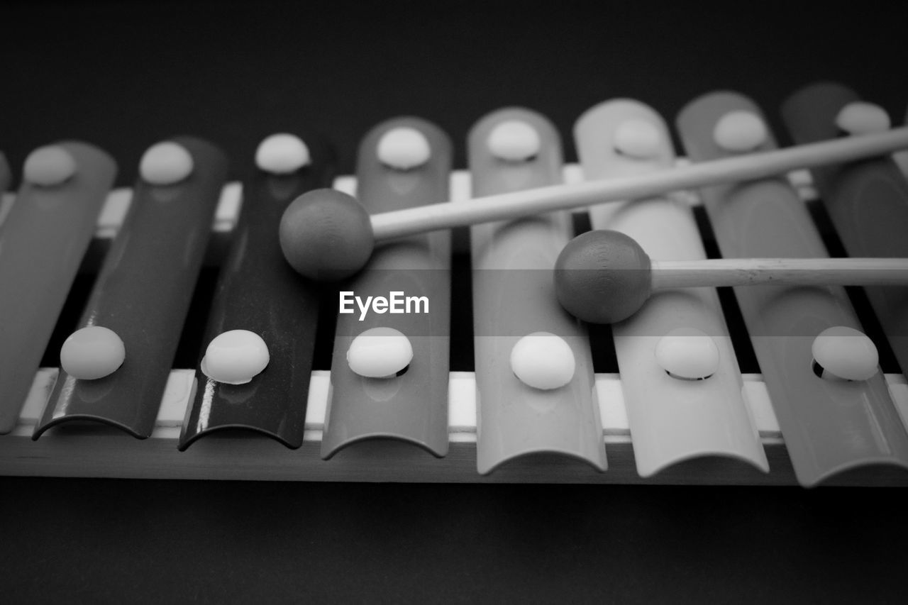 Close-up of mallets with xylophone against black background