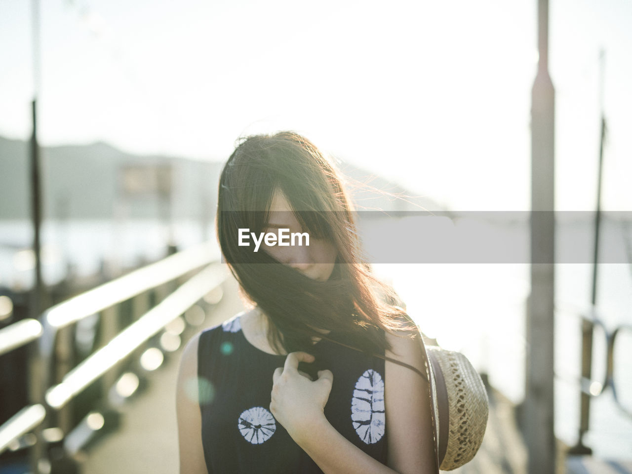 Young woman standing on pier during sunny day