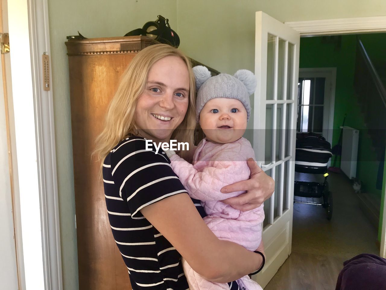 Portrait of happy mother carrying baby daughter at home