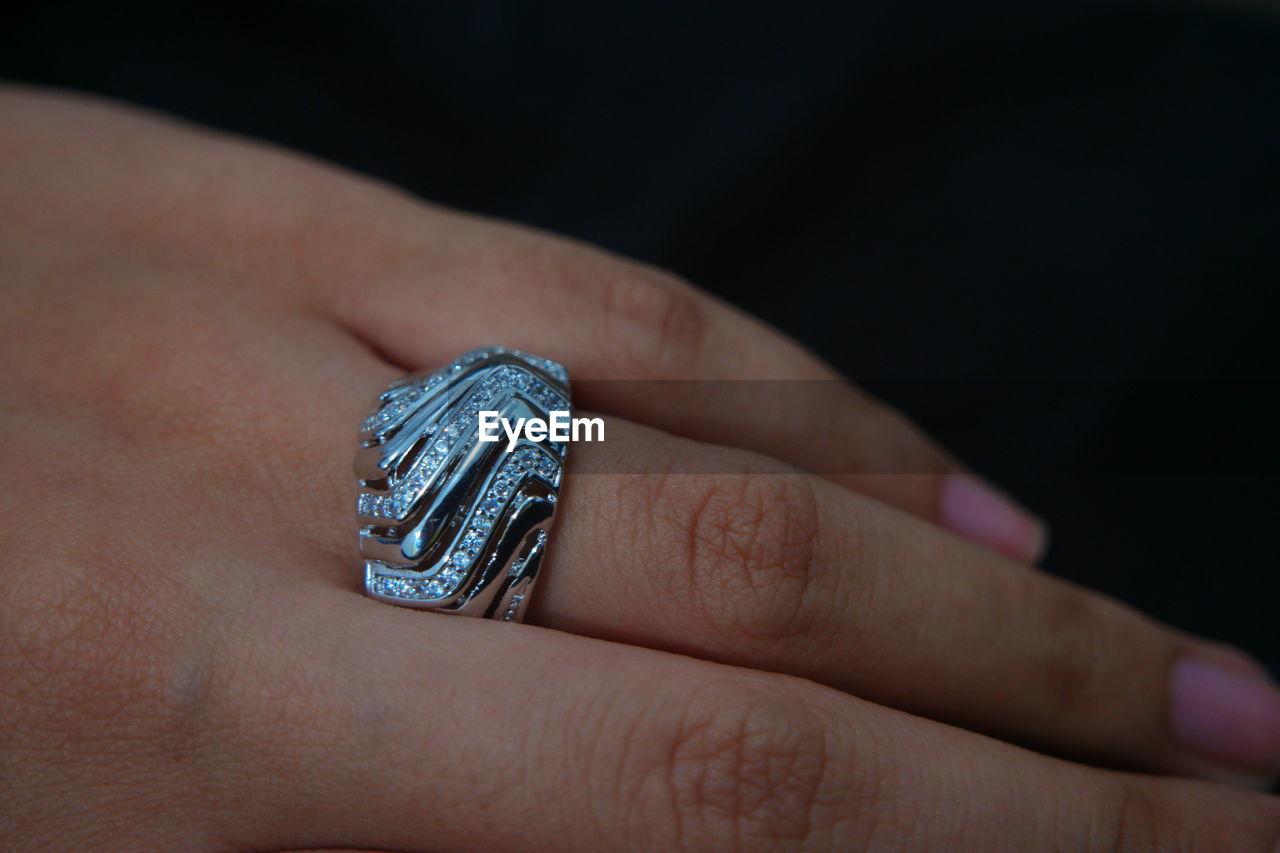 Close-up of woman showing ring against black background