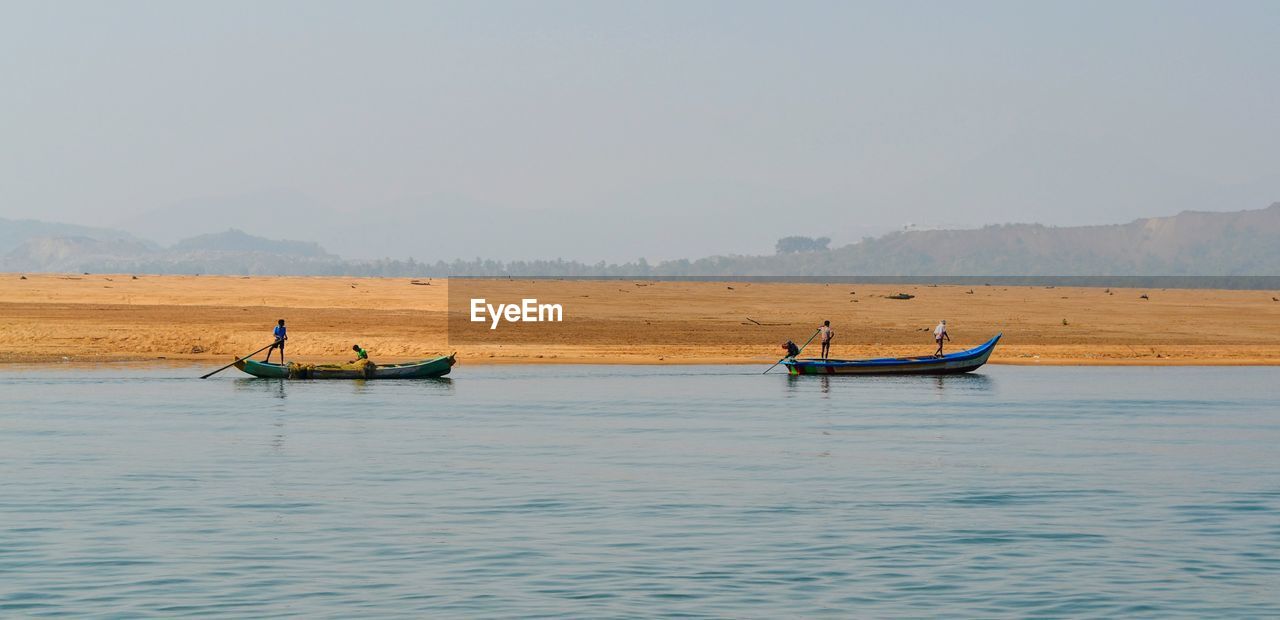 SCENIC VIEW OF PEOPLE ON SEA AGAINST SKY