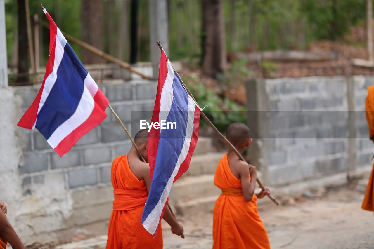 REAR VIEW OF PEOPLE AGAINST FLAG