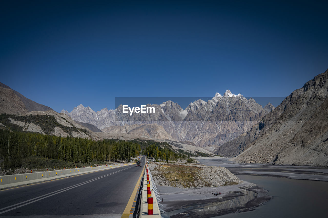ROAD BY MOUNTAINS AGAINST BLUE SKY