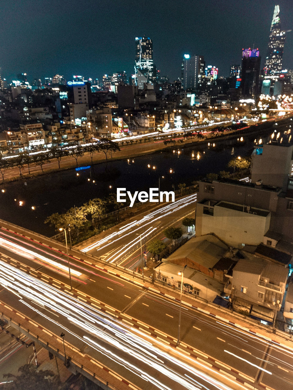 HIGH ANGLE VIEW OF LIGHT TRAILS ON ROAD AMIDST BUILDINGS IN CITY