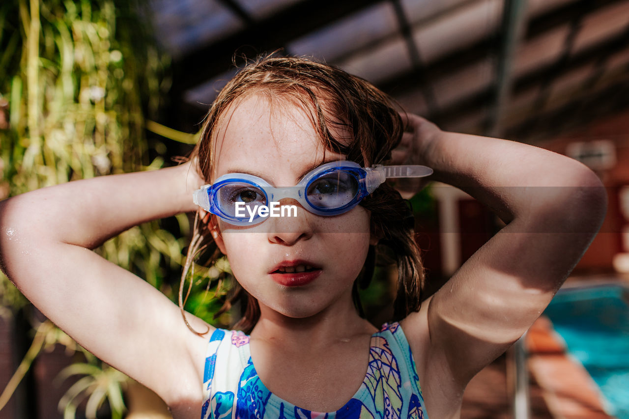 Young girl putting on goggles at a swimming pool