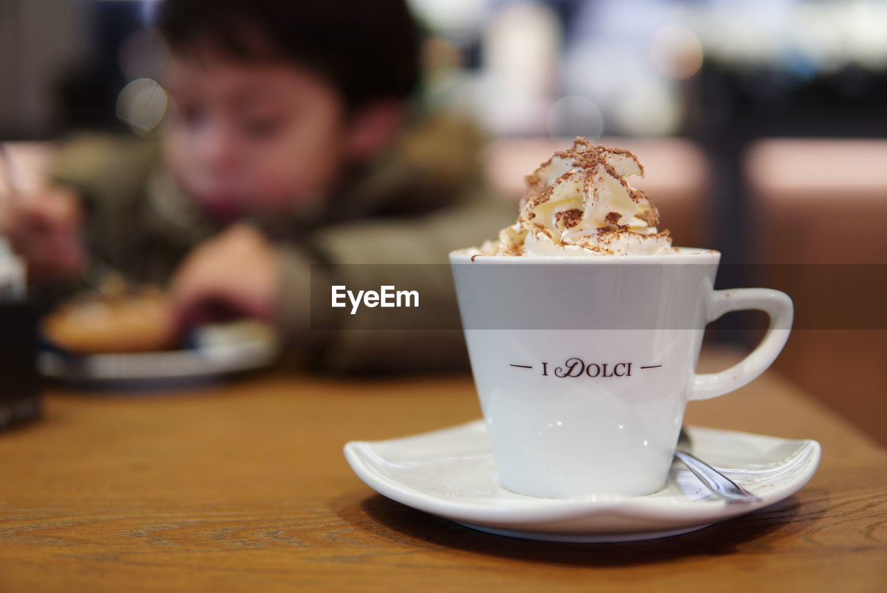 CUP OF COFFEE ON TABLE AGAINST BLURRED BACKGROUND