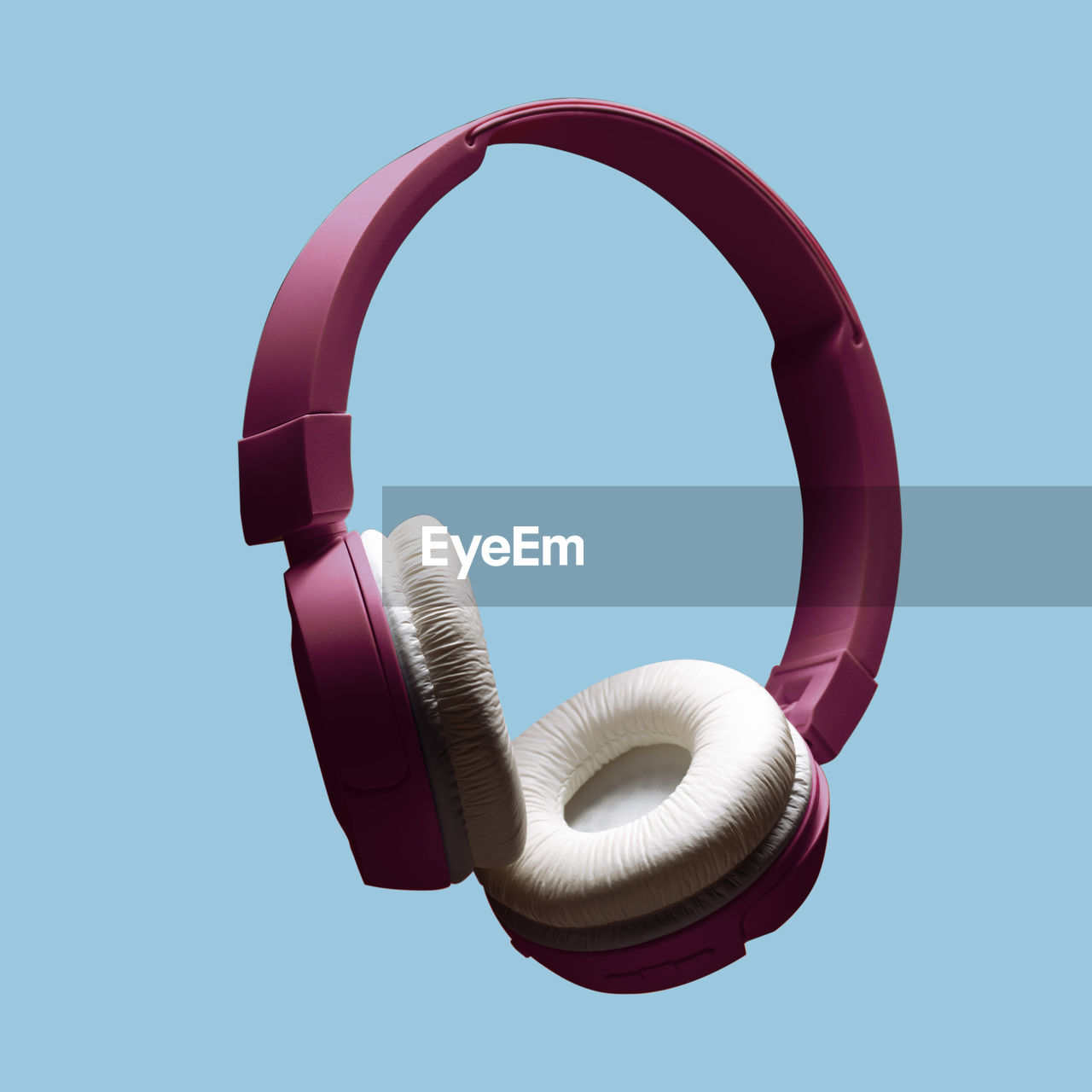 Modern wireless headphones in purple color on an isolated pastel blue background. the concept of