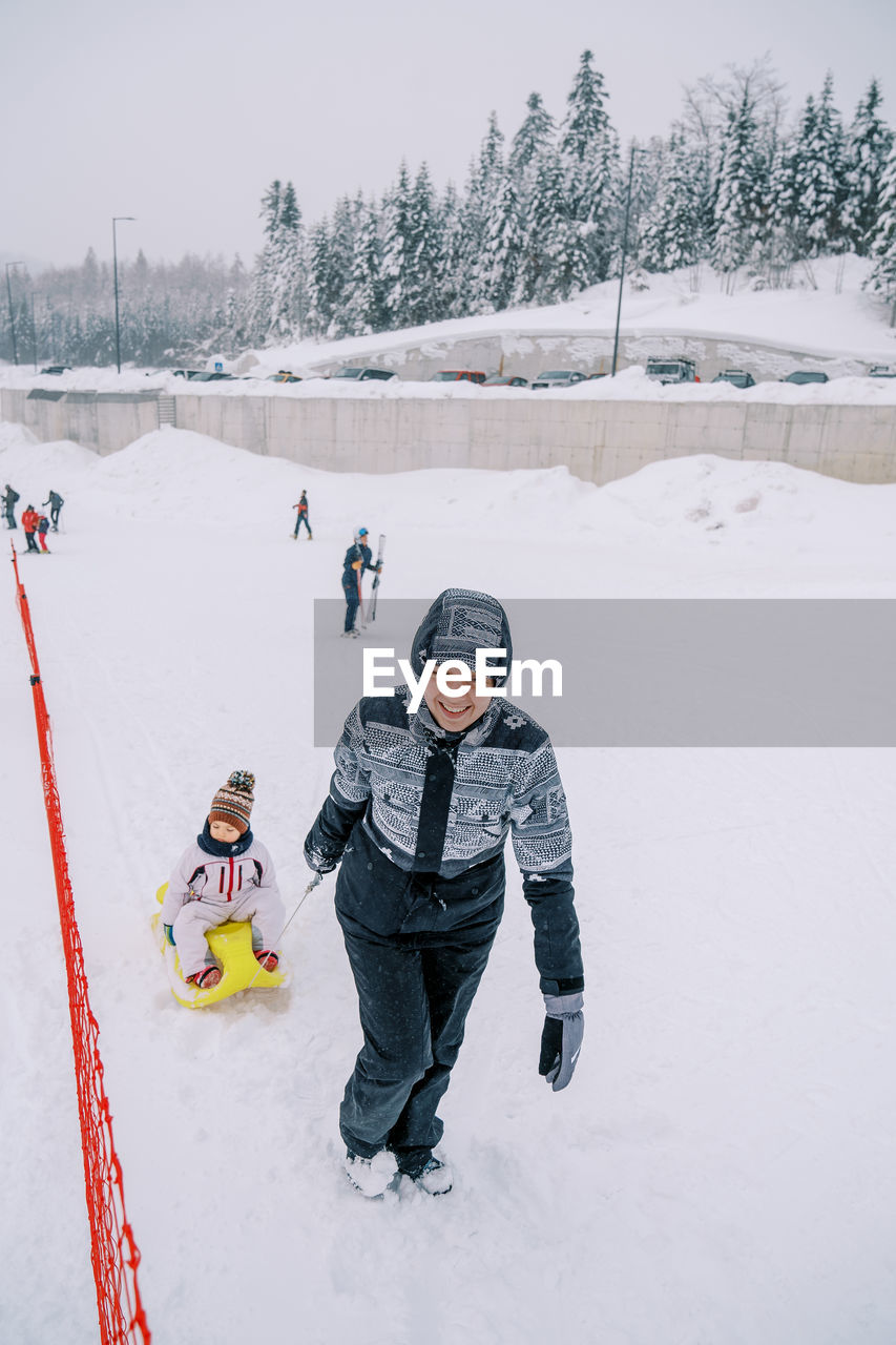 full length of man skiing on snow covered field against sky