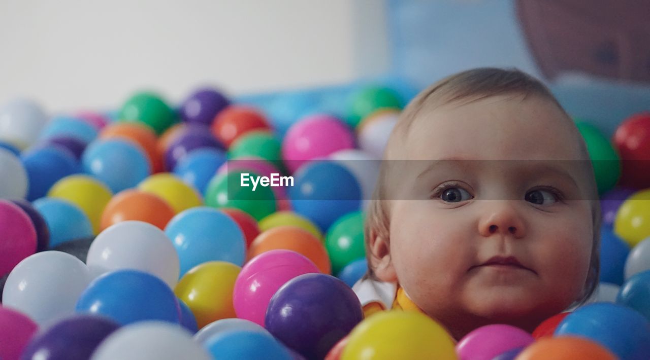 Close-up of cute baby boy looking away while sitting in ball pool