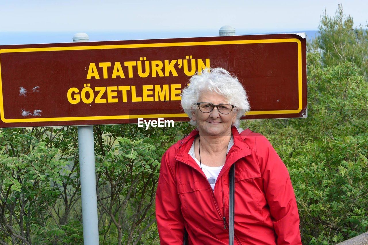 Portrait of woman sitting against information sign