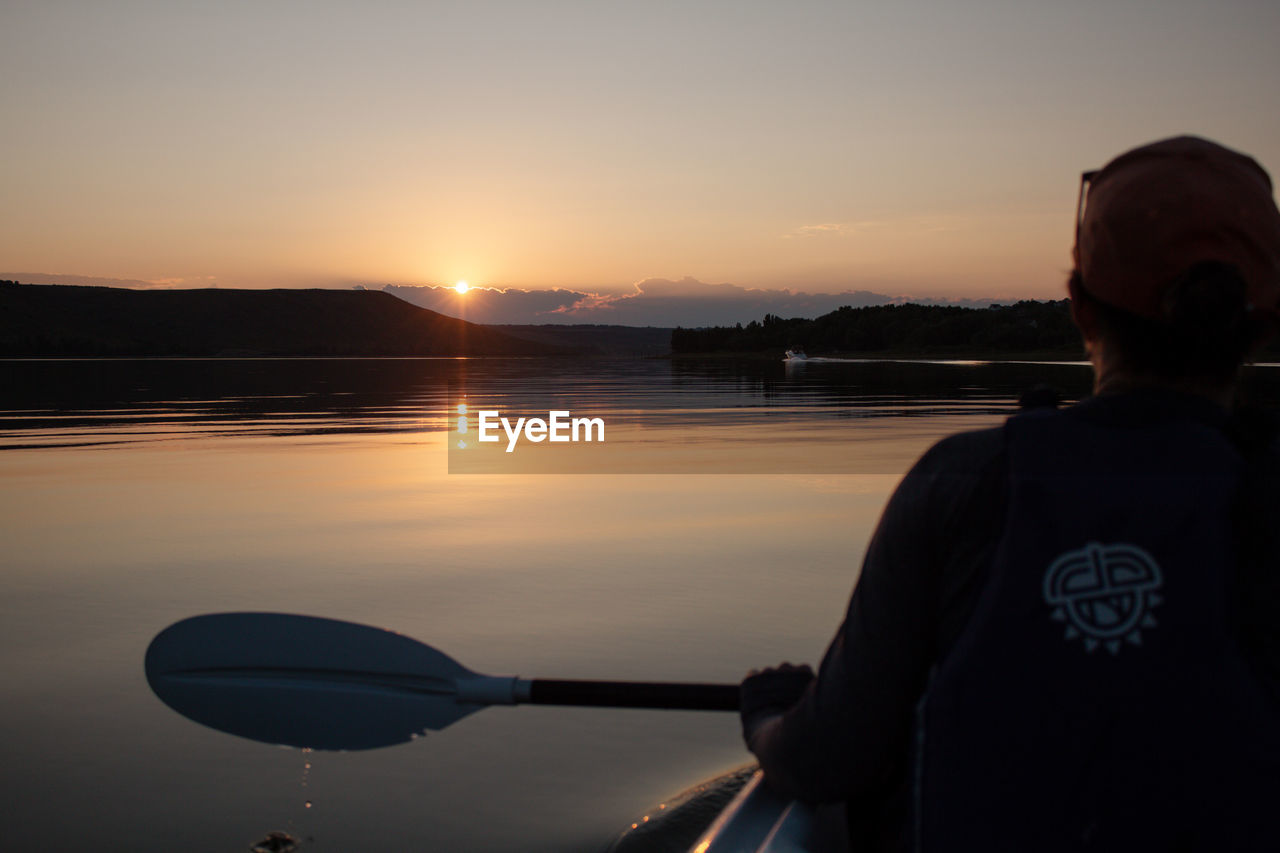 water, sky, sunset, one person, reflection, sea, nature, silhouette, evening, adult, vehicle, beauty in nature, men, dusk, transportation, waist up, rear view, tranquility, scenics - nature, lifestyles, leisure activity, tranquil scene, person, nautical vessel, outdoors, paddle, twilight, mode of transportation, sports